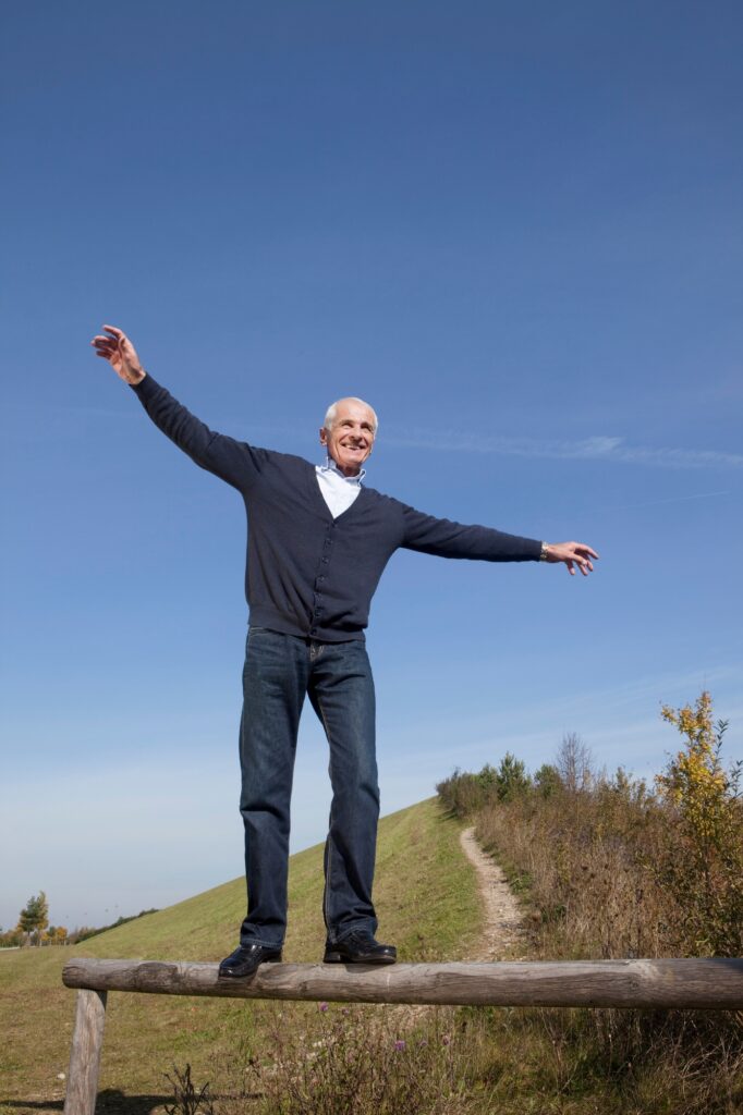 Senior man balancing along a wooden log
